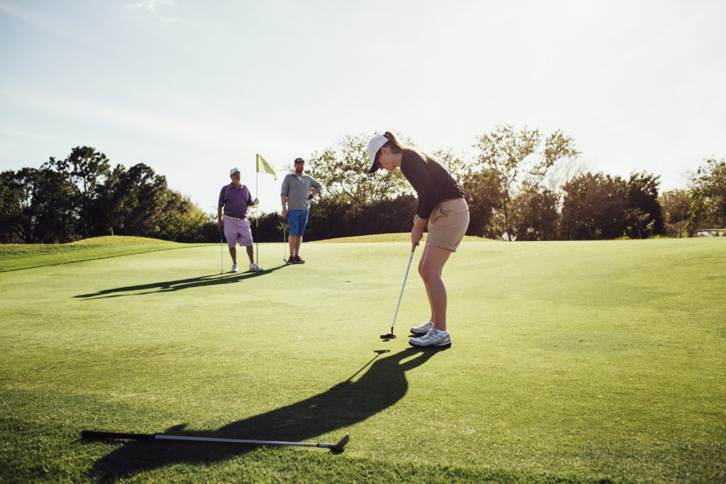 Family golfing at a local course wearing shorts, hat and golf shoes